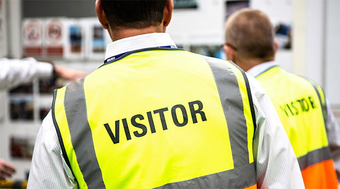 people wearing high-visibility vests marked visitor