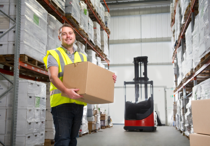 carrying cartons in a warehouse, wearing safety vest