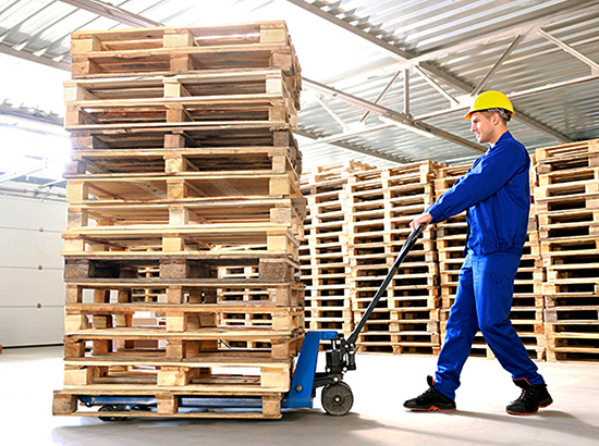 worker using pallet jack to move empty pallets