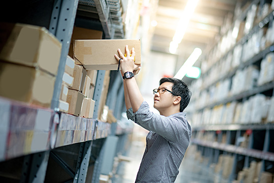 worker pulling box from industrial shelf