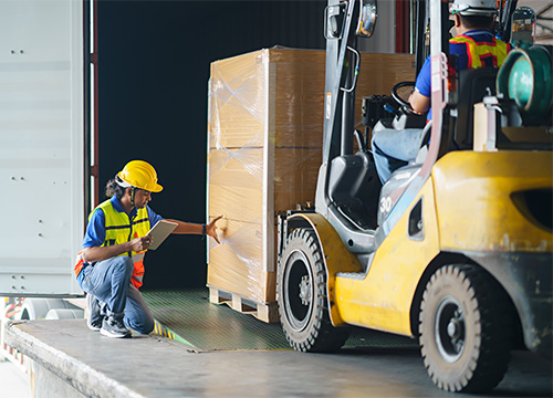 worker inspecting load driven by forklift