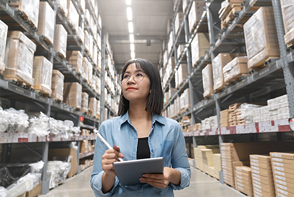 woman walking through warehouse with stylus and tablet