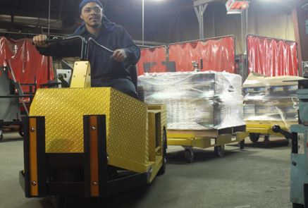 pallets towed behind a tugger in a warehouse