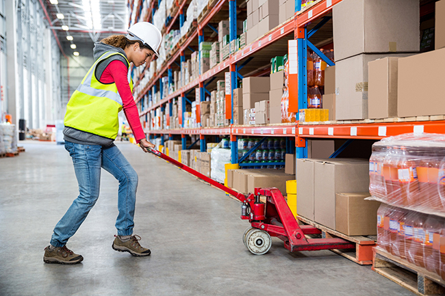 warehouse worker picking cartons from the floor level of a pallet rack