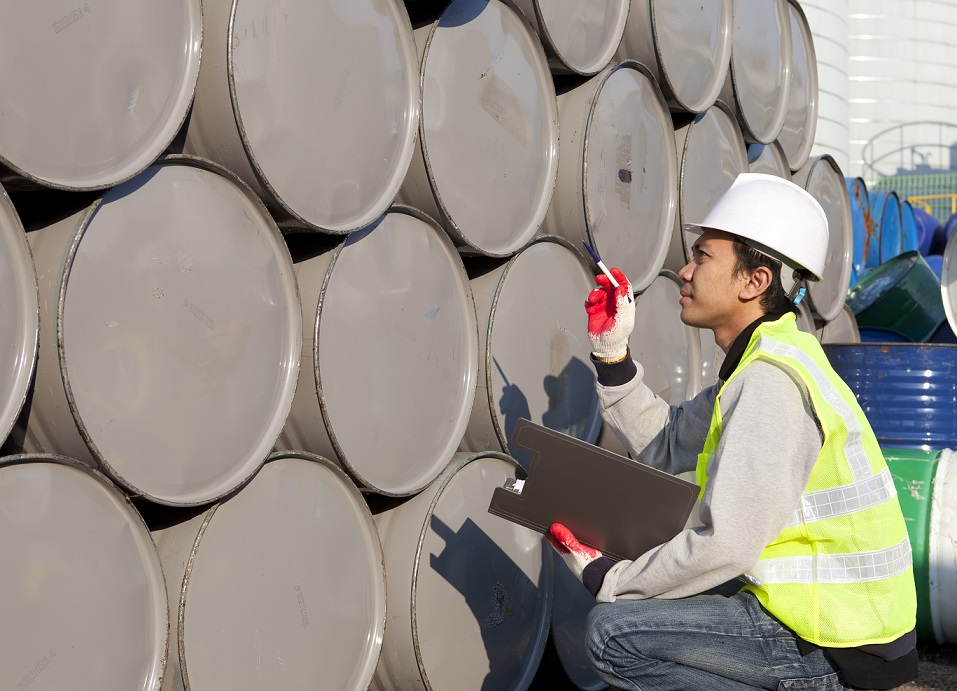 man with clipboard inventorying drums of hazardous material