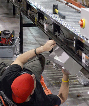 Worker installing a power roller conveyor in a warehouse.