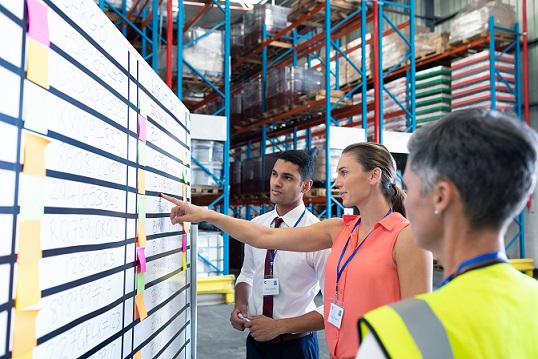 warehouse workers reviewing a whiteboard plan