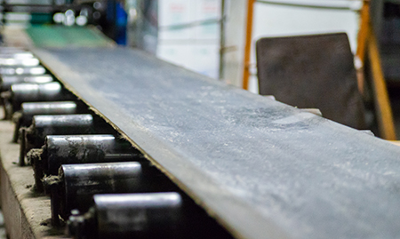 belt over roller conveyor in a gritty manufacturing facility