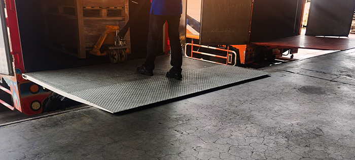 dock plate with a hand truck unloading at a warehouse shipping area.