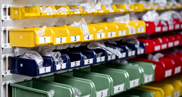 Hanging warehouse bins on a rail system with small parts and labels.