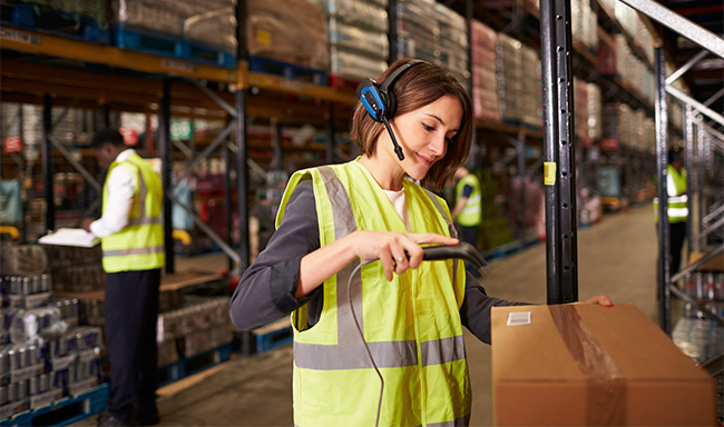 warehouse worker wearing a headset scanning a box