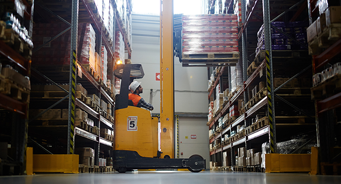 Warehouse rack with worker placing a pallet into tight space on a pallet rack