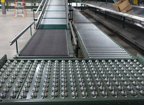 Ball transfer table mounted at a conveyor switchback in a large distribution center.