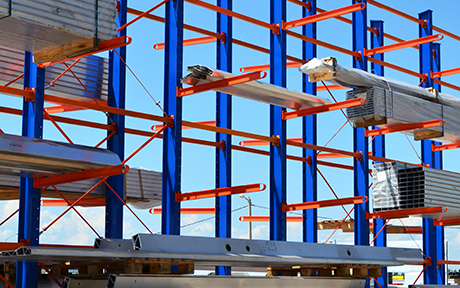 Outdoor cantilever rack in a lumber and pipe yard storing tubular steel.