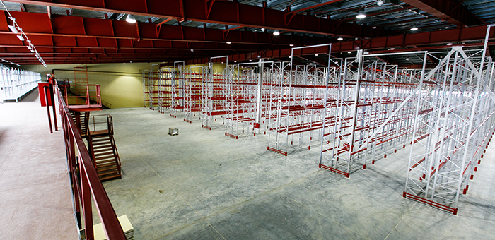 Photo of a warehouse floor, with a mezzanine installed on the left and a pallet rack system installed on the right.