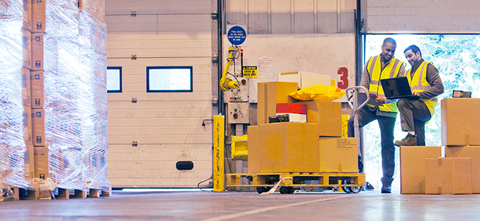 Workers with various loaded pallets on a warehouse dock staging area