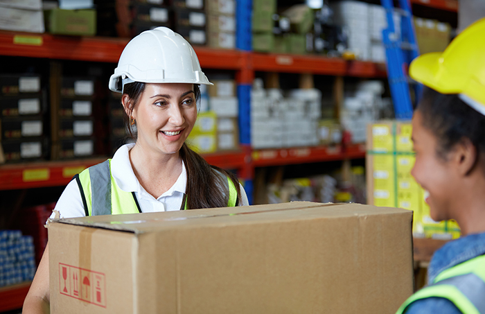female warehouse worker carrying a heavy carton.