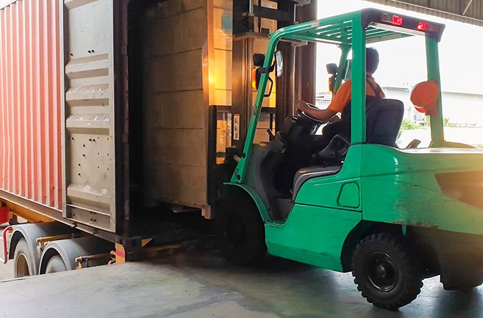 Forklift backing away with load at a warehouse truck dock area.