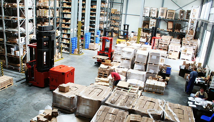 Busy warehouse shipping dock with pallets stored in racks and on the floor