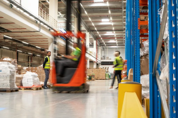 forklift moving by workers in a warehouse
