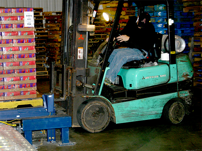forklift unloading pallets from the end of conveyor line