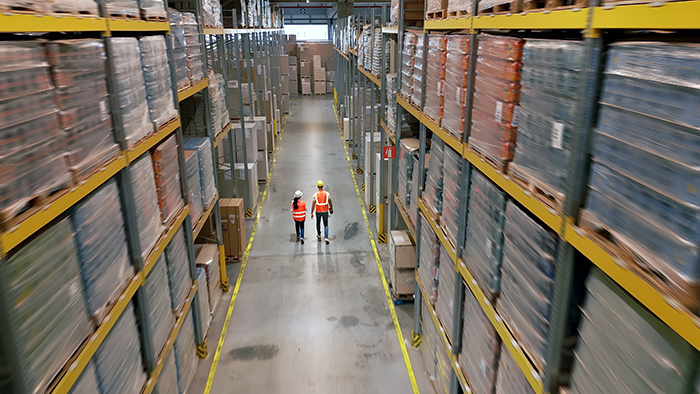 Warehouse with high bay rack storage system and workers in pick aisle